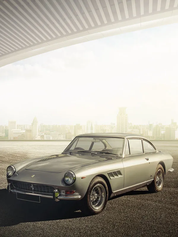 A classic silver Ferrari with city skyline in the background